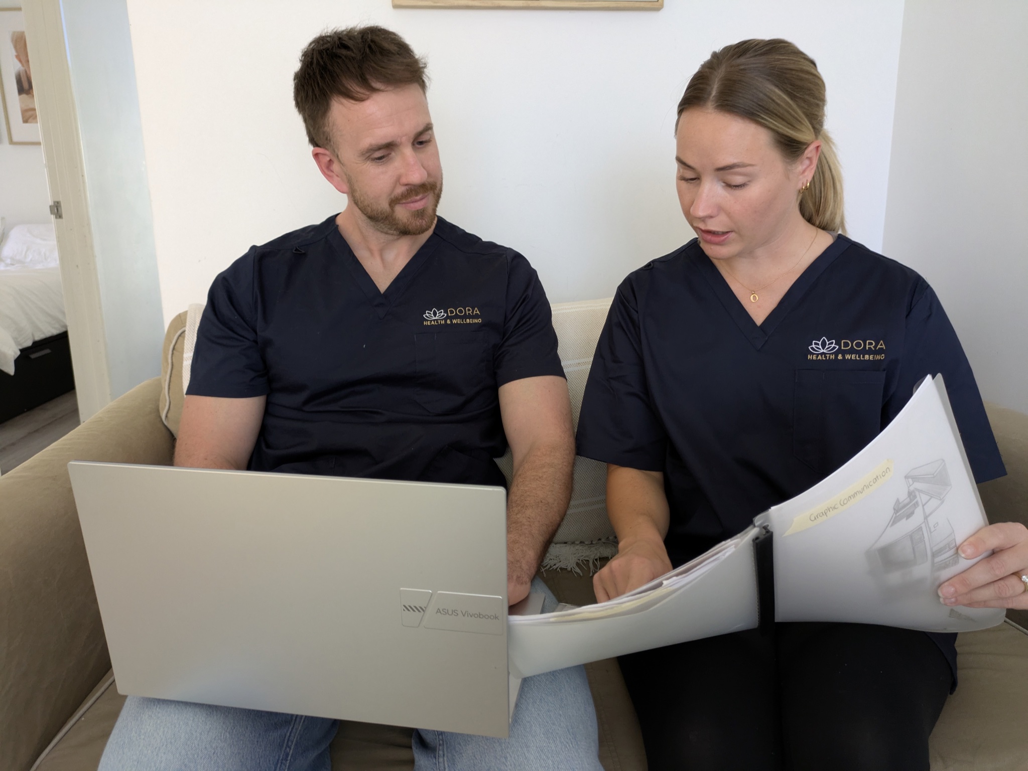 Two Dora staff in scrubs planning client care together